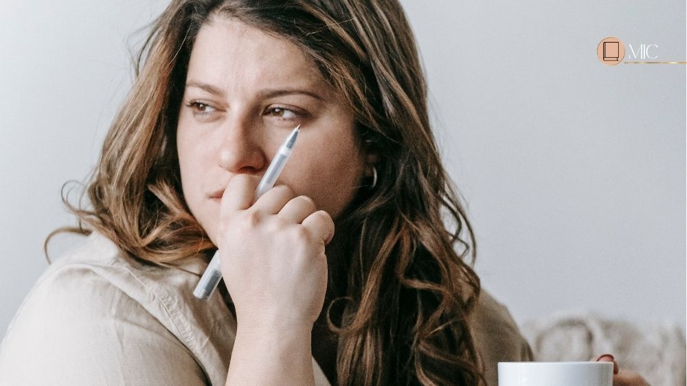 mulher segurando uma caneca e uma caneta pensando
